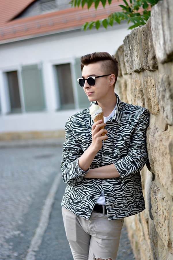 Zebra-print Jeansjacke Modeblogger genießt Eis, lehnt an Mauer.