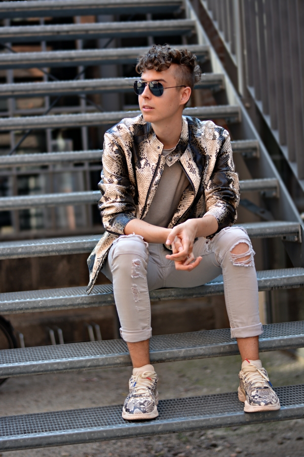 Junger Mann in Animal Print Lederjacke sitzend auf einer Metalltreppe
